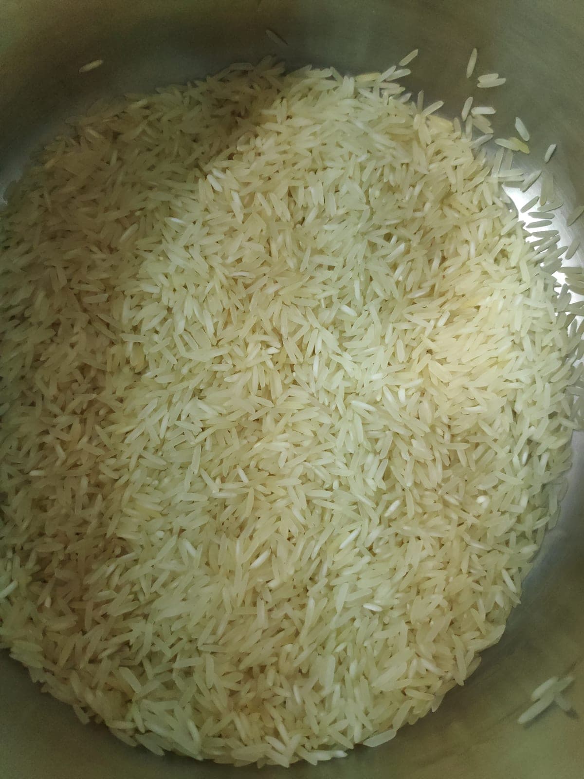 Raw long-grain basmati rice in a metal bowl